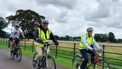 Cyclists cycling along road in front of railings