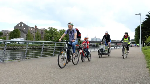 Cyclists riding along the greenway with Donoghy's Mill and the Peace Bridge in background