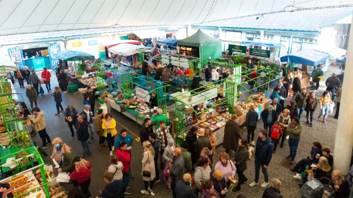 Overhead view of covered market with busy market stalls surrounded by crows of shoppers