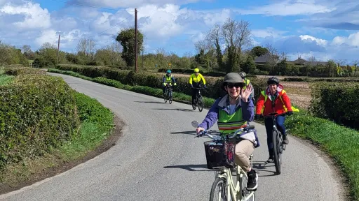 A group of people cycling on a country road on a sunny day