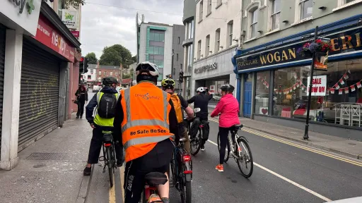 A group of cyclists on Shop Street on an overcast evening